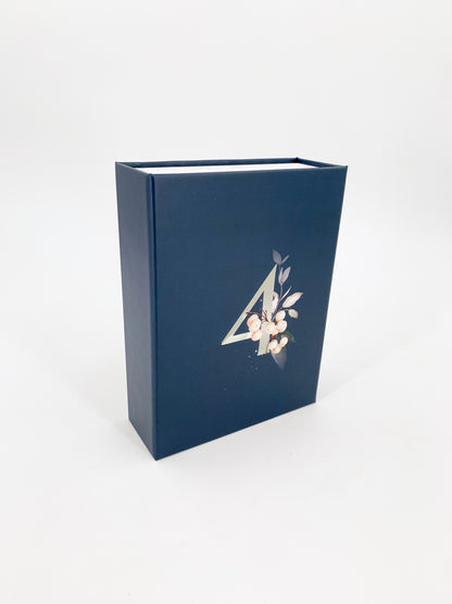 Eine blaue Magnetbox mit der Zahl 4 und kleinem dekorativen Pflanzen Print, hochkannt auf weißem Hintergrund