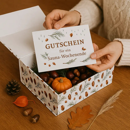 Offene Magnetbox gefüllt mit Kastanien und Kürbis Hände halten einen Gutschein