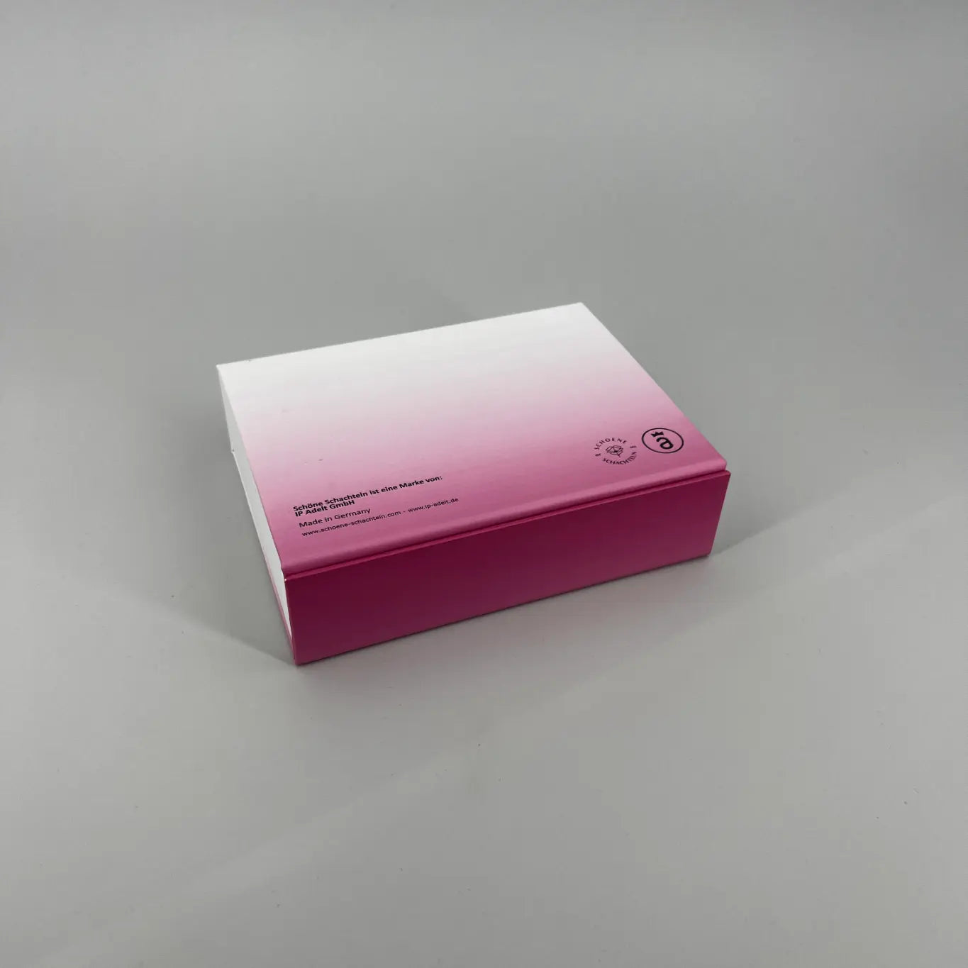 Weiß Pinke Schachtel mit Rückseite mit Impressum Print, liegend auf hellgrauem Hintergrund